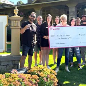 A small group posed with a large check outside a building