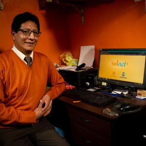 Fernando sitting at a desk with a laptop open to "Solnet."