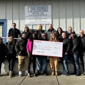 A group of people stood outside Ferndale Food Bank, holding a donation cheque
