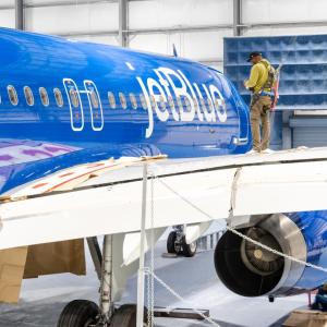Man working on blue and yellow airplane in hangar