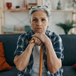 Woman seated on a couch holding her cane.