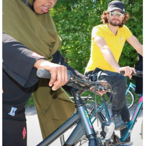 Two people riding bikes outside.