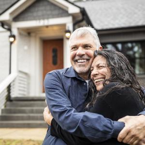 Young couple hugging in front of their new home.