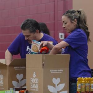 Two people wearing FedEx shirts packing boxes at the Food Bank