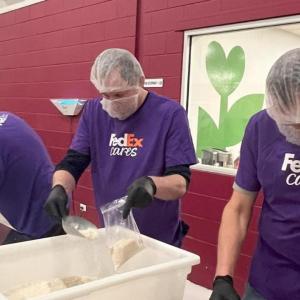 Several people wearing FedEx shirts preparing food at the Food Bank