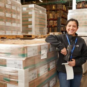 person smiling next to a warehouse of boxes