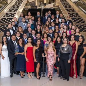 More than 50 people standing at the base of stairs wearing formal attire