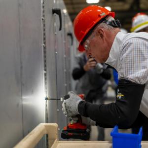 Congressman Steve Womack drills in a sheet metal screw on a custom air handling system at the Trane Fort Smith plant