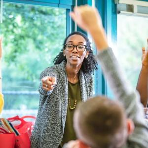 A teacher pointing to students with their hand raised 