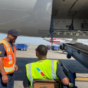Two crew members talking to each other next to an aeroplane 