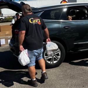 a person with bags in their hands loading the trunk of a car