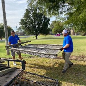 two people carry part of a fence together