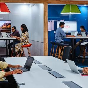 People at different tables, all working on laptops.