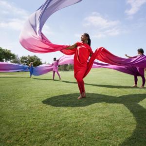 women dancing with colorful fabric on a lawn