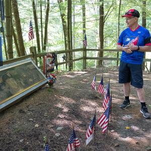 Gene Griffin standing in front of his son's memorial, American flags decorate it
