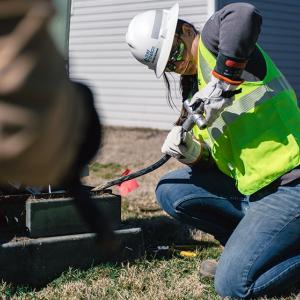 Georgia Hummel working on a power line outside on the ground.