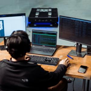 person sitting at a desk with many monitors