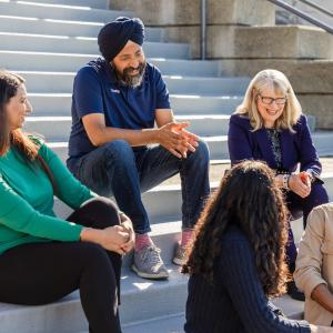 CEO Aman Bhutani shown with a group of people chatting on steps outside of a building.