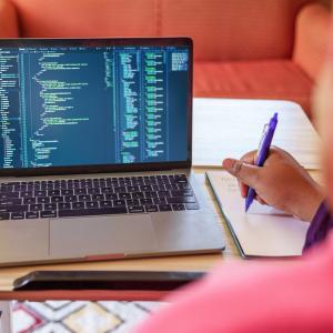 A person seated at a desk in front of a MacBook.