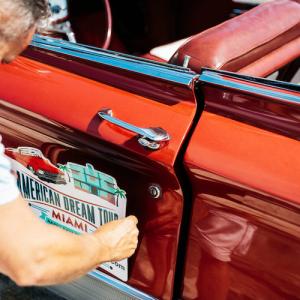Man attaching a sign to the side of a car.