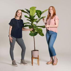 Two women standing in front of a plant.