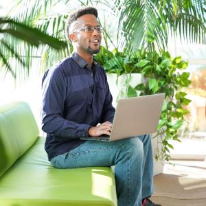 Young person of color seated on a couch.