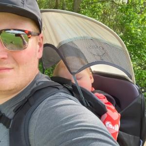 Greg Farley carrying his sleeping son in a backpack.