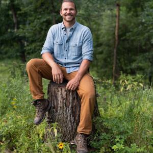 Tim Clemens seated on a stump.