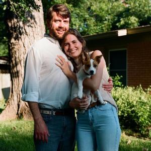 Clement, his wife and their dog in a yard.