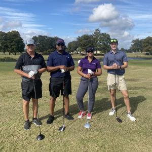Four people holding golf clubs on a course