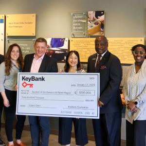 Teams from Goodwill of the Olympics and KeyBank shown with a $300,000 grant check.