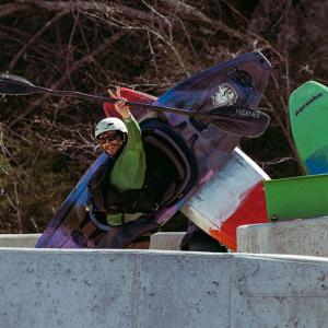 Person carrying a kayak while waving