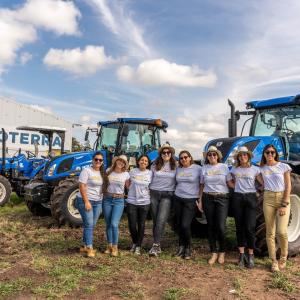 A group of women stood in front of some tractors 