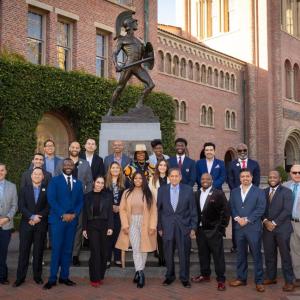 a large group of people stood together in front of a statue 