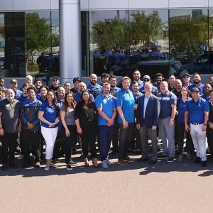 A large group photo of people stood outside a building 