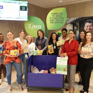 A large group photo of people holding food supplies 