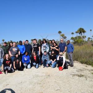 group of students and adults on the bank of a river