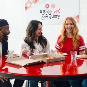 four people sat around a red table eating pizza