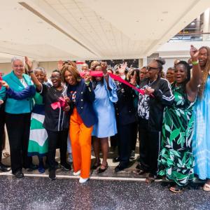 A group of people cheering at a ribbon cutting.