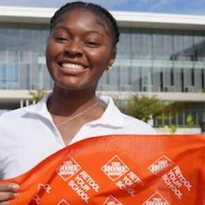 Female Black student at an HBCU holding a Retool your School banner.