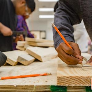 Two men shown working on a carpenter's bench.