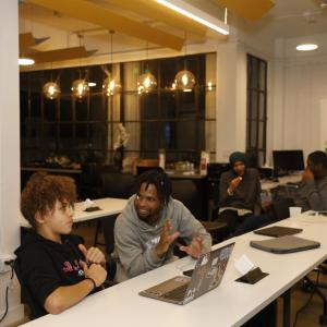 two people sitting in front of laptop