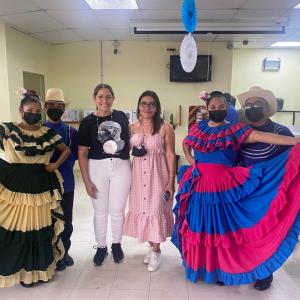 Dancers in colorful traditional dresses next to two employees in a lunch room