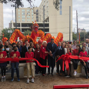 Large crowd of diverse people cutting a red ribbon