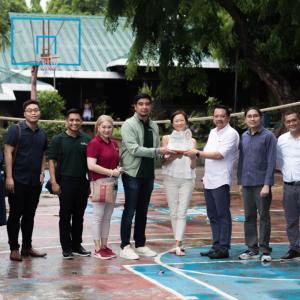 a group of people on a basketball court, three holding an award