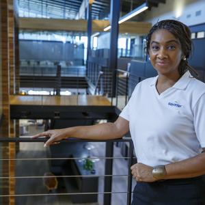 Person stood against a stair railing in an office, wearing a shirt with the Rayonier logo on 