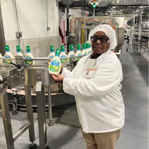 An employee hold up a bottle of ranch dressing in a manufacturing warehouse.
