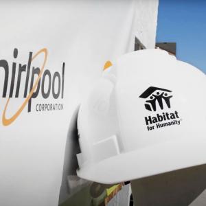 hard hat with habitat for humanity logo next to a whirlpool logo on a vehicle