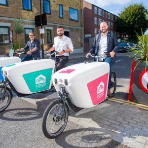 Three people lined up with cargo bikes on a street.