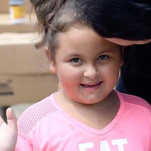 Young girl smiling and waving.